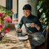 Bright and inviting workspace with a person enjoying coffee at a sunlit table, surrounded by lush greenery.