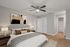 Bright and inviting bedroom with modern decor, featuring a comfortable bed, elegant artwork, and a sleek ceiling fan.