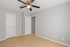 Bright bedroom with sleek wooden flooring, elegant gray walls, and a modern ceiling fan, creating a serene and inviting space.