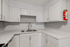 Modern kitchen with sleek white cabinetry, elegant marble countertops, and a convenient double sink.