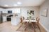 Chic apartment kitchen with modern white cabinets, stainless steel appliances, and an elegant dining area with stylish chairs.