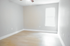 Bright and spacious empty room with sleek hardwood floors and soft gray walls, ready for personalization.