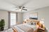 Inviting bedroom with plush bedding, stylish wooden furniture, and abundant natural light, complemented by a serene landscape artwork.