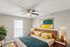 Inviting bedroom with modern decor, featuring a wooden bed frame, artful paintings, and lush indoor plants.