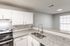 Modern kitchen with sleek granite countertops, stainless steel appliances, and glossy white cabinetry, illuminated by natural light.