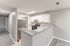 Modern kitchen with sleek granite countertops, stainless steel appliances, and soft gray cabinetry opening into a bright, airy living space.