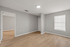 Bright, spacious room with sleek wood flooring and modern gray walls, featuring large window and elegant, minimalistic design.