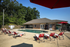 Inviting apartment complex pool area with comfortable red loungers, surrounded by lush greenery and a cozy clubhouse.