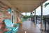 Inviting covered porch with colorful Adirondack chairs and scenic views, perfect for relaxing.
