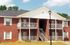Charming brick apartment building with welcoming balconies and well-maintained surroundings under a clear blue sky.
