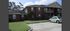 Charming brick apartment building with lush green lawn and spacious parking area under a clear blue sky.