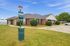 Charming brick apartment with manicured landscaping and convenient dog waste station, set under a clear blue sky.