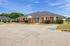 Charming red brick duplex with a welcoming front porch, set against a backdrop of lush greenery and a clear blue sky, perfect for comfortable suburban living.