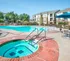 Spacious outdoor pool area with a hot tub and shaded seating at a modern apartment complex.