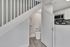 Modern apartment offering a sleek under-stairs restroom adjacent to a stylish kitchen with stainless steel appliances and chic backsplash.