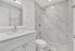 Elegant modern bathroom featuring sleek white vanities, polished marble tiles, and a spacious glass-enclosed shower.