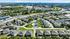 Scenic aerial view showcasing a well-planned housing community with modern homes, green spaces, and a central sparkling swimming pool, set against a vibrant urban backdrop.
