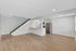 Bright open-concept living area featuring sleek hardwood floors, modern kitchen with stainless steel appliances, and stylish staircase.