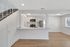 Modern open-plan kitchen with sleek white cabinetry, stainless steel appliances, and inviting hardwood flooring leading to a bright living area.