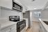 Contemporary kitchen with sleek stainless steel appliances, bright white cabinetry, and a spacious countertop, flooded with natural light from a large window.