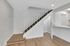 Modern apartment interior showcasing a sleek staircase with stylish wooden flooring and an open concept kitchen.