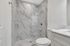 Elegant bathroom featuring a modern glass-enclosed shower with sleek marble tiles and stylish white cabinetry.