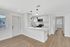 Modern open-concept kitchen with sleek white cabinetry, stylish pendant lighting, and inviting hardwood floors.