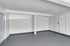 Spacious, bright room with clean white walls, modern gray flooring, and ample potential for customization in an inviting apartment.