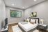 Elegant bedroom with modern decor, featuring a plush bed, stylish artwork, and a large window offering green views.