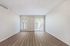 Bright living room with elegant wood flooring, large windows, and sliding glass door leading to a private patio.