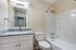 Modern bathroom showcasing elegant granite countertop, sleek white cabinetry, and a pristine bathtub with a curved shower rod.