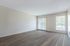 Spacious apartment interior featuring elegant wood-style flooring and abundant natural light through large windows with vertical blinds.