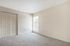 Bright and inviting bedroom with soft carpet, a large window, and built-in closet doors, offering a serene view outside.