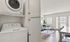 Bright and modern living room with hardwood floors, featuring a cozy couch, elegant coffee table, natural light from large windows, and in-unit laundry for convenience.