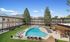 Beautiful apartment complex with a crystal-clear swimming pool, ample lounge seating, and stunning mountain views in the background.