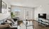 Chic and inviting living room with a modern sofa, vibrant green plant, and abundant natural light through large windows, perfect for relaxation.