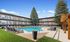 Inviting apartment complex surrounds a sparkling pool, framed by lush greenery and sun loungers, perfect for relaxation and leisure.