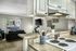 Kitchen with beige cabinets, stainless steel sink, white stove, lights under cabinets and a passthrough to the living room.