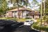 Apartment building brick exterior and parking spaces. Trees and shrubbery surround exterior