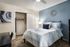 Bedroom with blue accent wall, full sized bed, closet and study desk