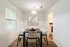 Dining area with white and black dining set, modern wall art and entrance to the kitchen to the right.