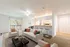 Carpeted living and dining area with white and black furniture, grey area rug, and a passthrough to the kitchen.