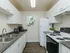 Galley kitchen with white cabinets, double sink, and white refrigerator and stove..