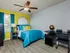 Bedroom with ceiling fan and furniture with yellow accent wall.