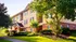 Apartment home exterior surrounded by grass, trees and a sidewalk.