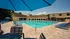 Community pool surrounded by lounge chairs with clubhouse in background.