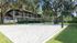Beach volleyball pit surrounded by green grass, trees and apartment building in background.