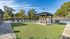 Grassy area inside pavered walkway.  Gazebo and picnic table in the middle.  Pool and tennis court in background.