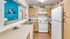 Galley style kitchen with wood style flooring, white appliances, double sink.
