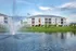Apartment building exterior with lake and fountain in foreground.